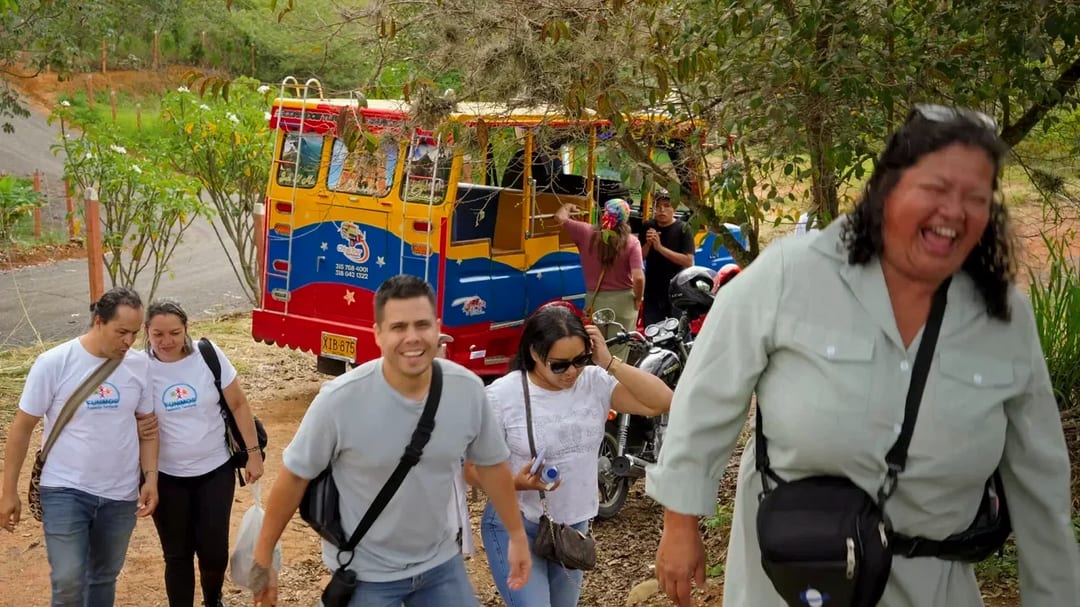 Un grupo de visitantes baja sonriendo de una chiva a la entrada de un sendero