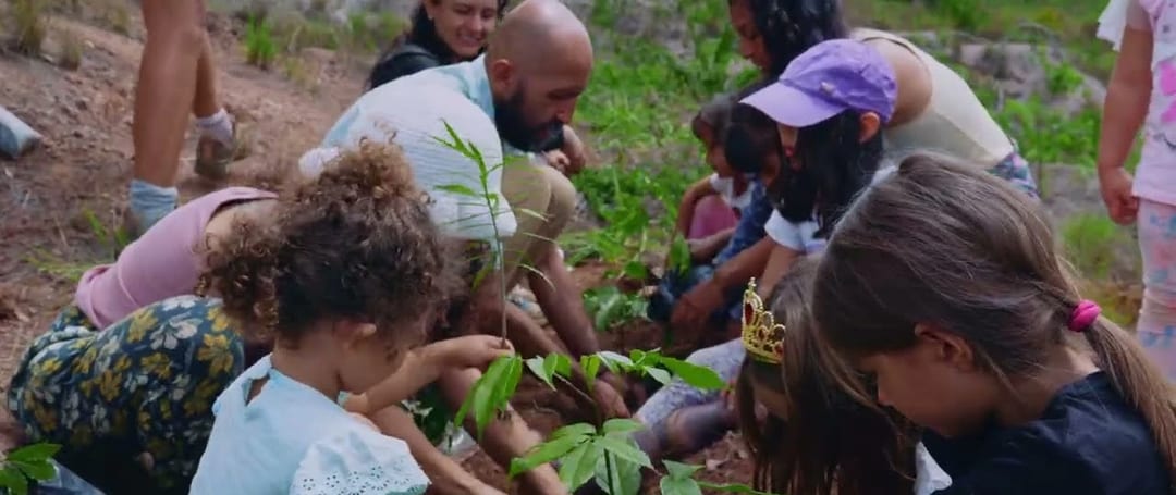 Niñas, niños y adultos siembran plántulas de árboles nativos en la tierra del bosque seco