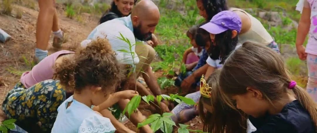 Niñas, niños y adultos siembran plántulas de árboles nativos en la tierra del bosque seco